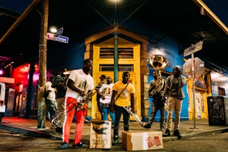 people holding musical instruments while standing on street during nighttime