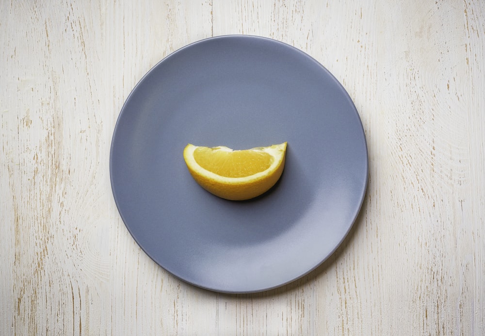 a blue plate with a half of an orange on it
