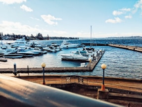 Aerial drone view capturing a serene harbor with boats docked under a clear sky.