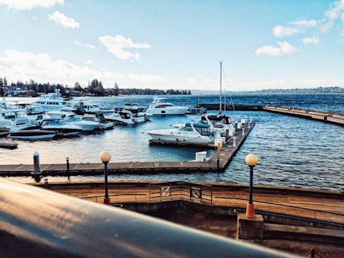 Aerial drone view capturing a serene harbor with boats docked under a clear sky.