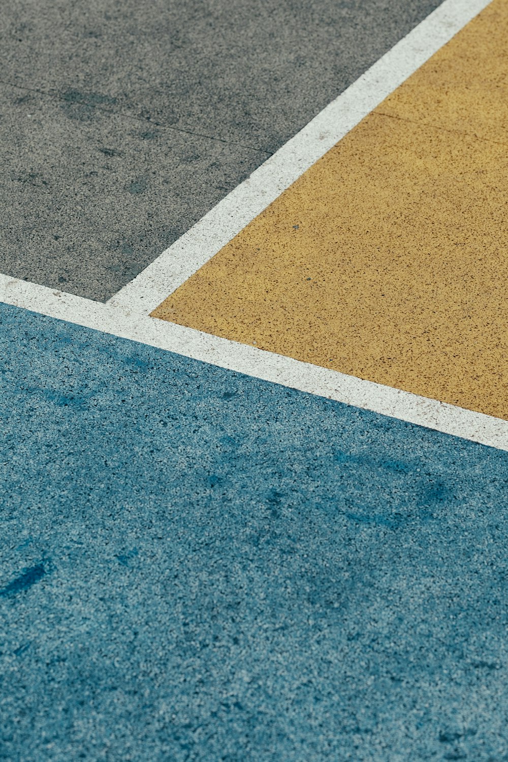 Primer plano pavimento pintado de gris, amarillo y azul