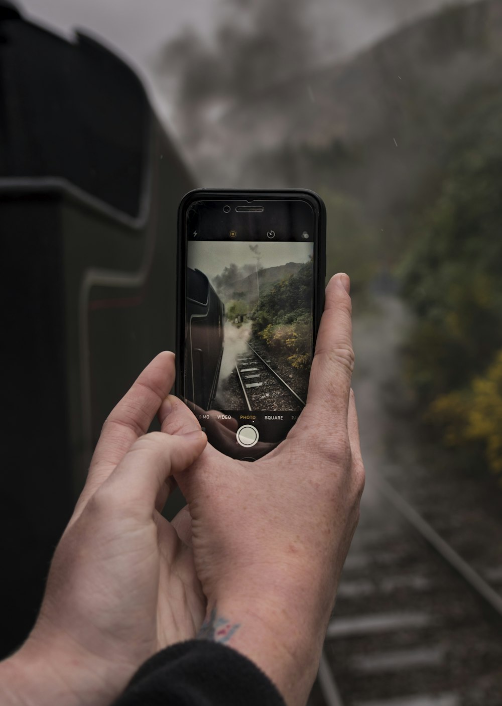 person taking photo of railway using iPhone