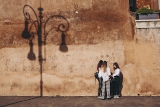 three women standing near brown wall