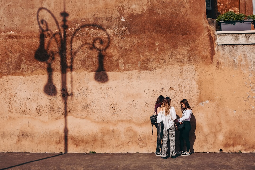 three women standing near brown wall