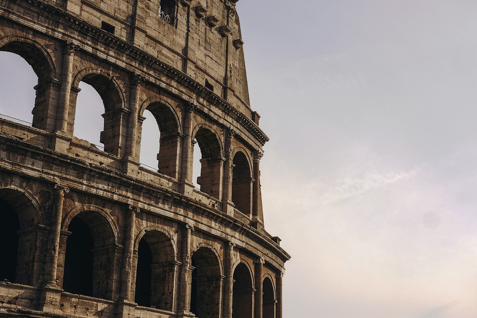 Close-up view of the Colosseum's ancient arched facade in Rome under a soft evening sky