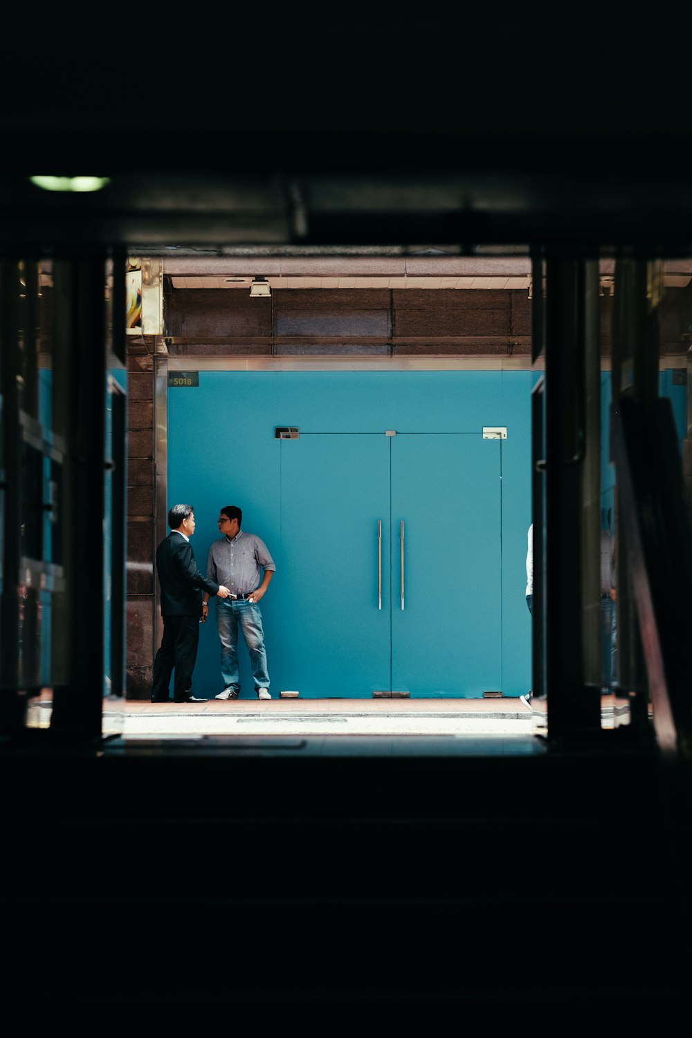 two men standing beside teal wooden doors