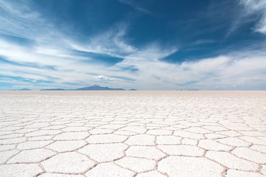 dry soil under white clouds and blue sky at daytime in Uyuni Salt Flat Bolivia