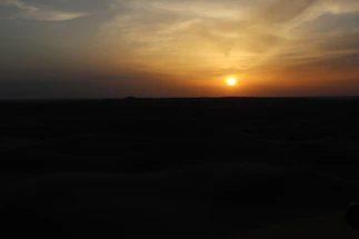 A warm sunset over the Merzouga desert with a photographer capturing the scene.