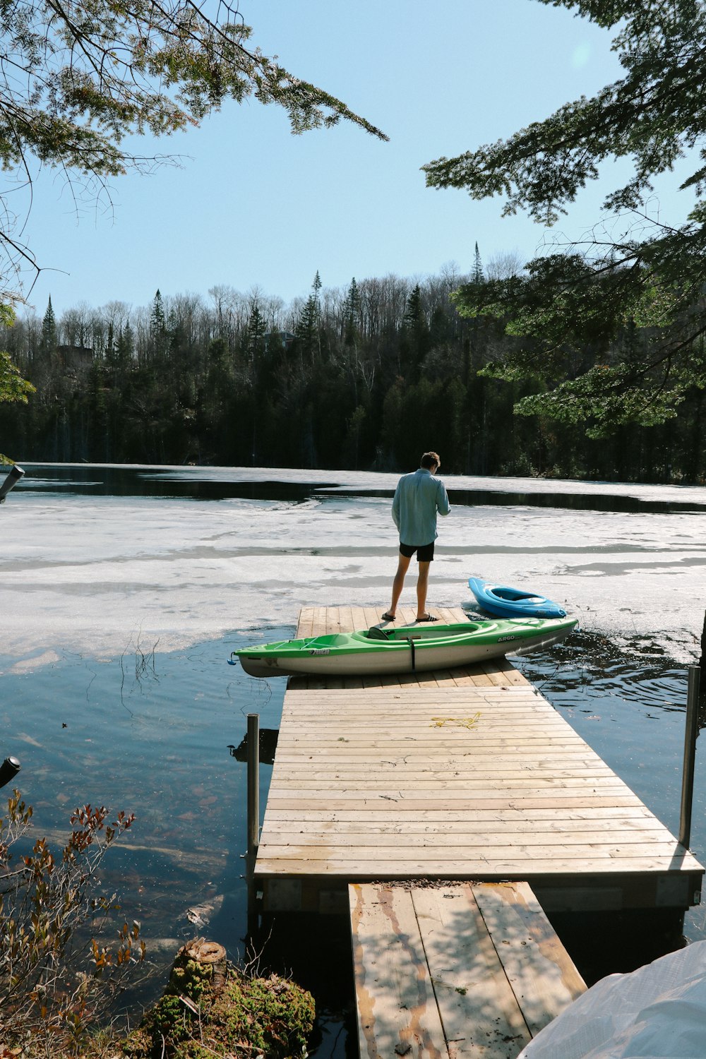 person standing on dock near kayaks