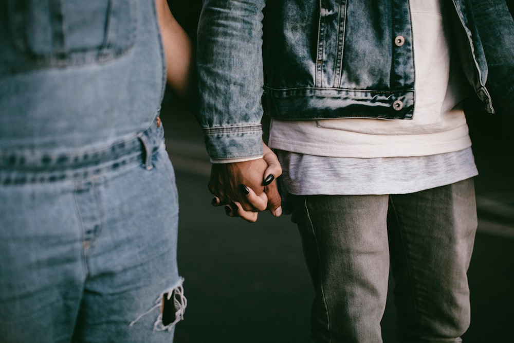 two person holding hands while walking