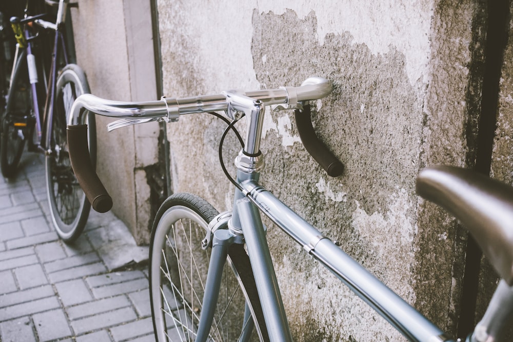 bicicletta da strada grigia appoggiata al muro grigio