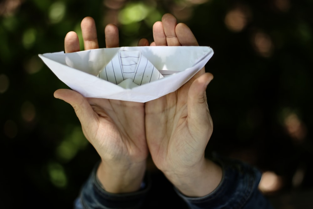 person holding paper boat in focus photography