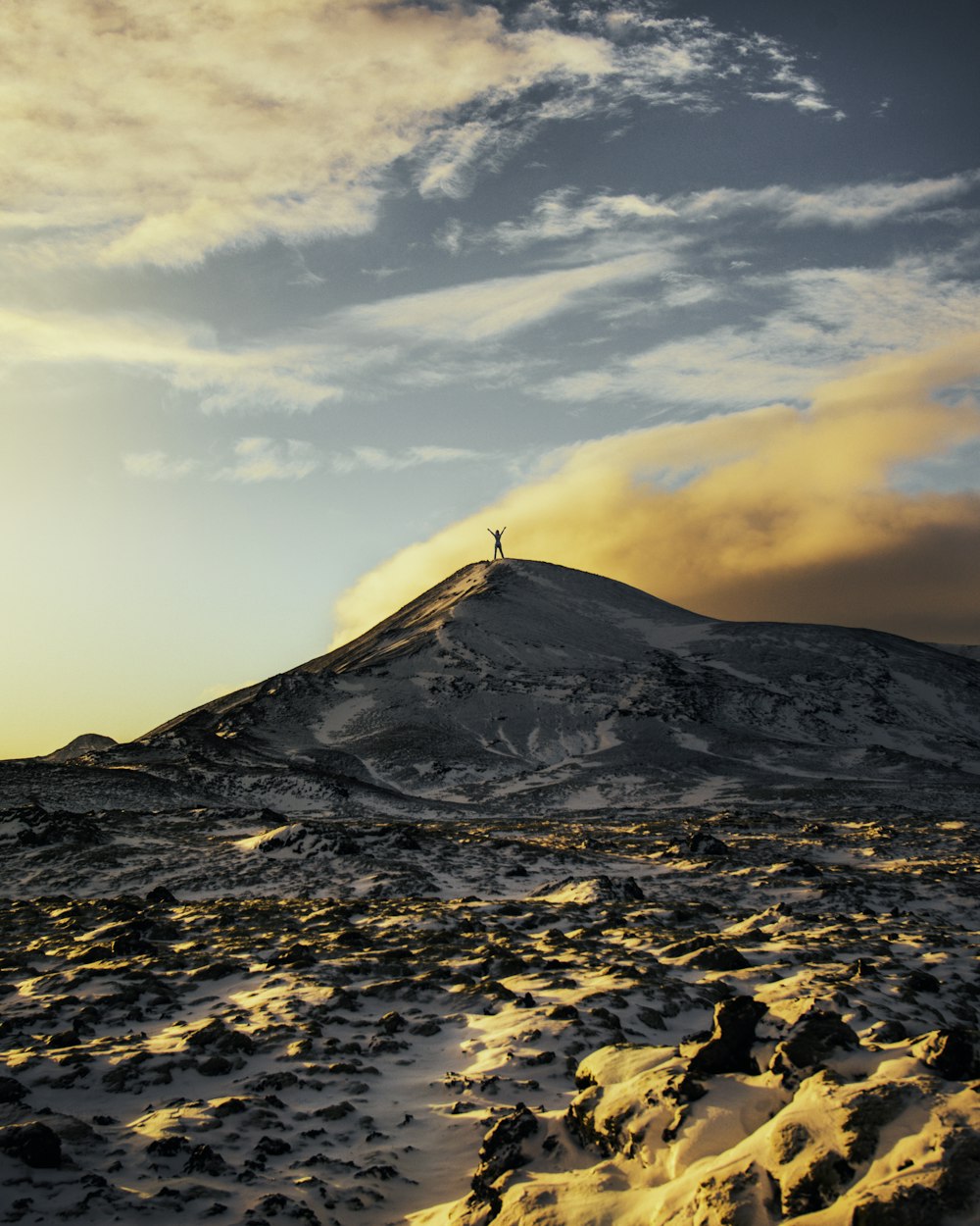 pessoa em pé no topo da montanha coberta de neve durante o dia
