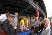Volunteers helping elders in a traditional Chinese village setting.