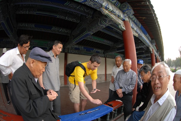 A joyful group of friends gathered around a table, laughing and playing mahjong with elegant sets.