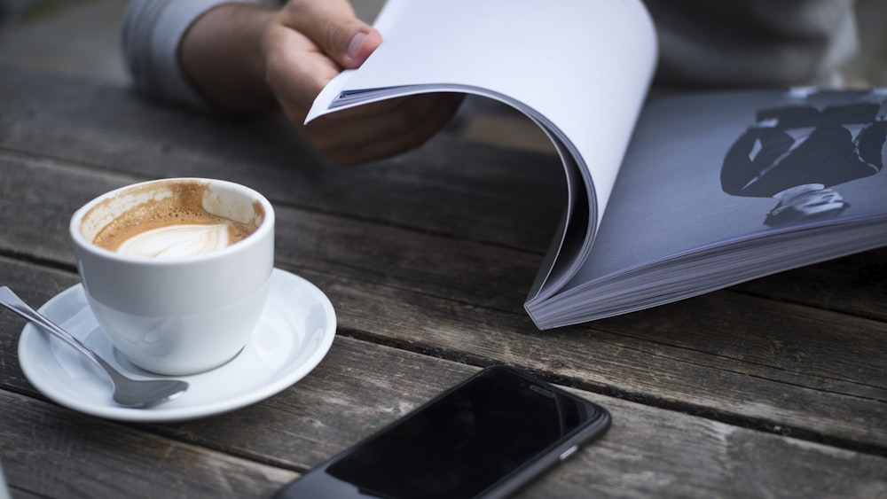 person holding book on table