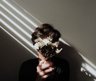 person holding white daisy flowers