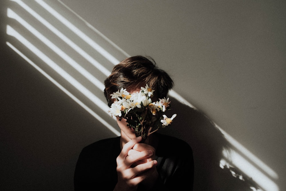 personne tenant des fleurs de marguerite blanche