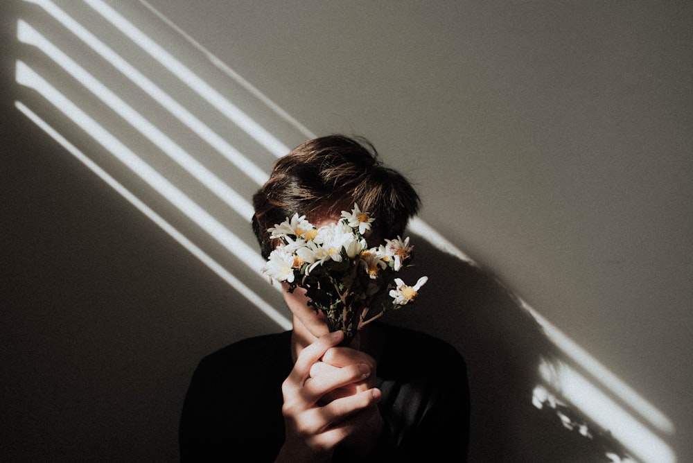person holding white daisy flowers