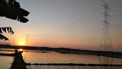 Engineers inspecting high-voltage power lines at sunset with a backdrop of city lights