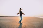 woman standing on sand near seashore during golden hour enjoying the rejuvenating outdoors
