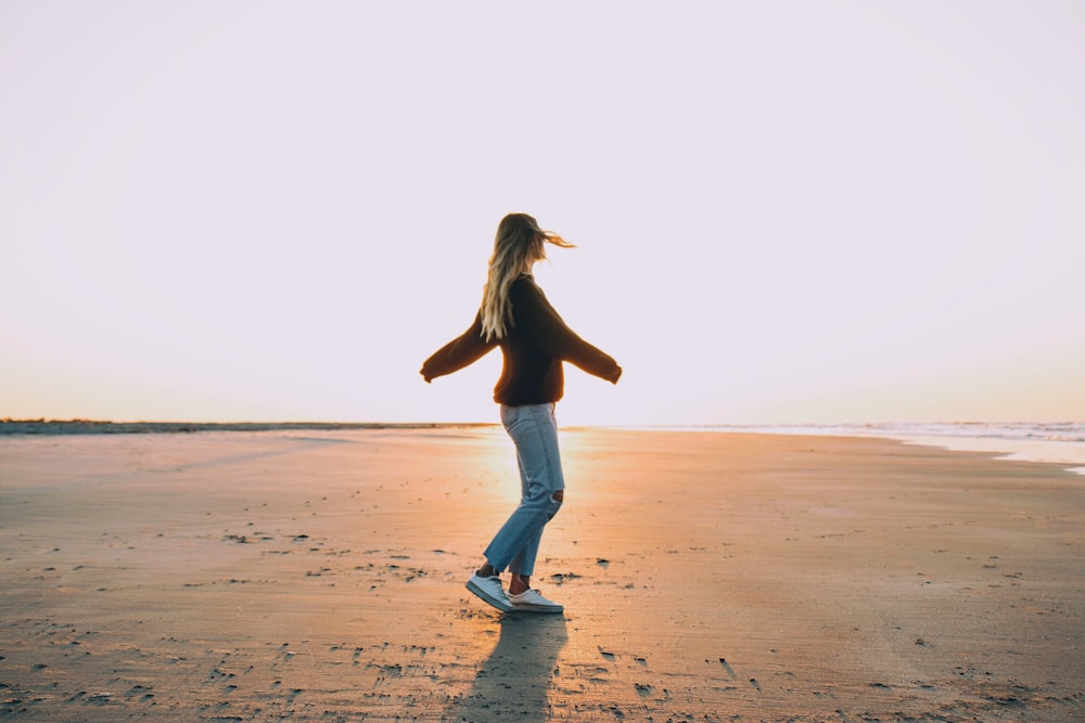 Donna in piedi sulla sabbia vicino alla riva del mare durante l'ora d'oro