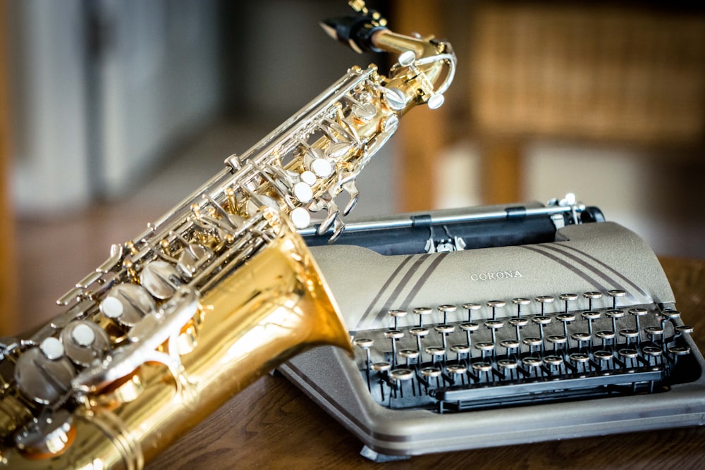 brass saxophone and typewriter on table