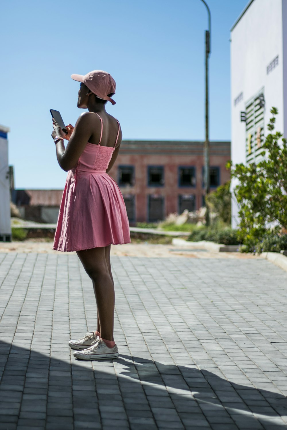 Frau im rosa Spaghettiträger-Minikleid mit Smartphone