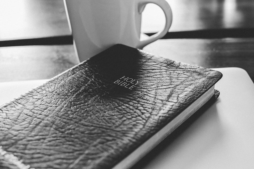 a black and white photo of a book and a cup