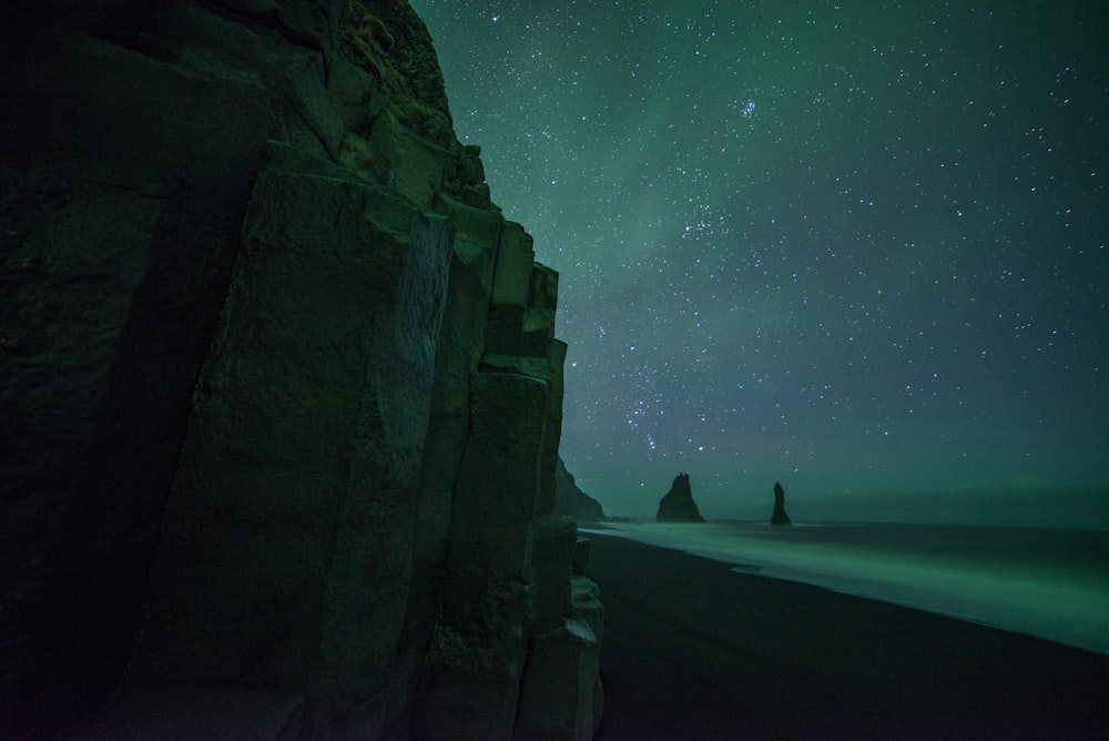 brown rocky mountain under green aurora borealis