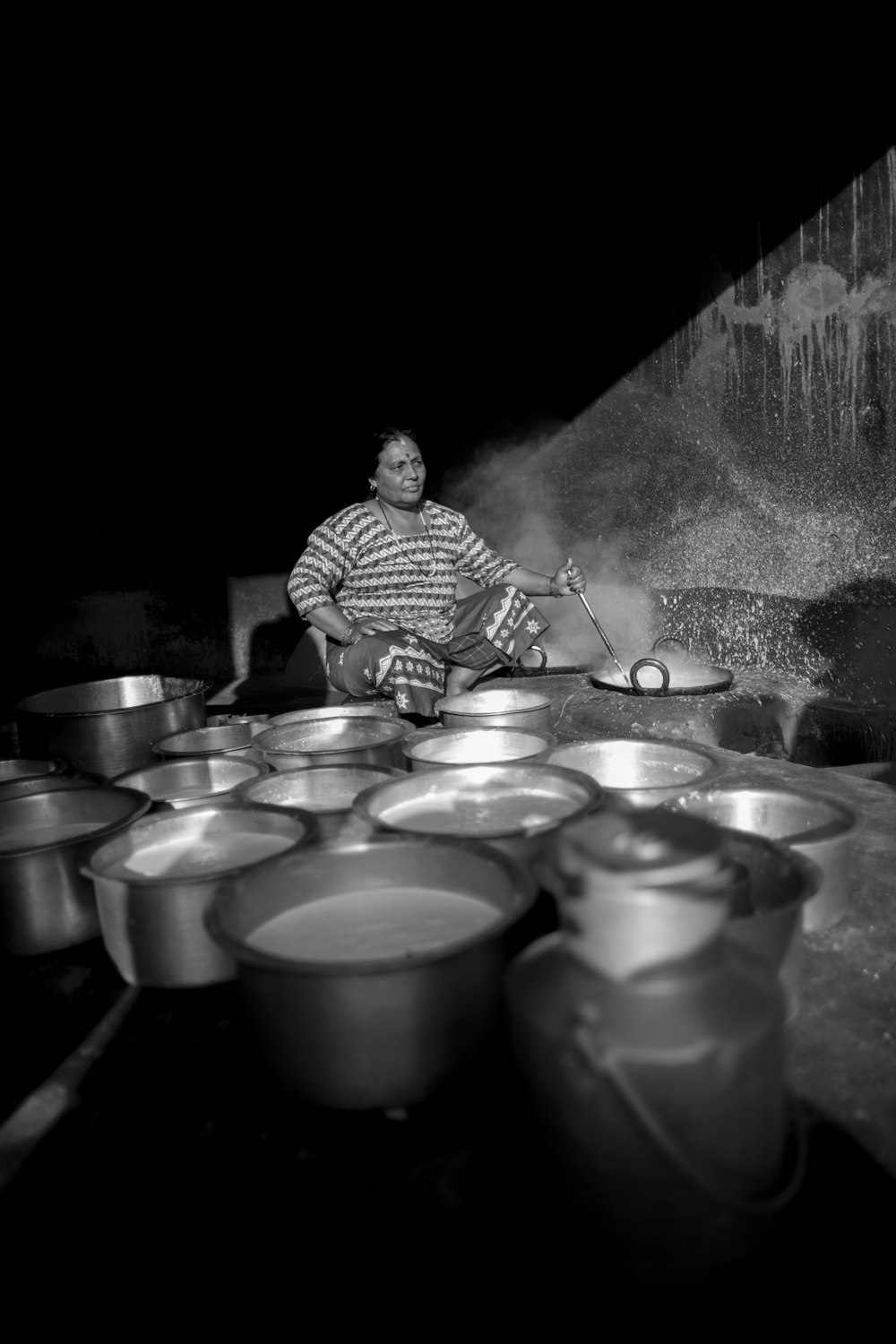 柄鍋を持ちながら料理をする女性のグレースケール写真