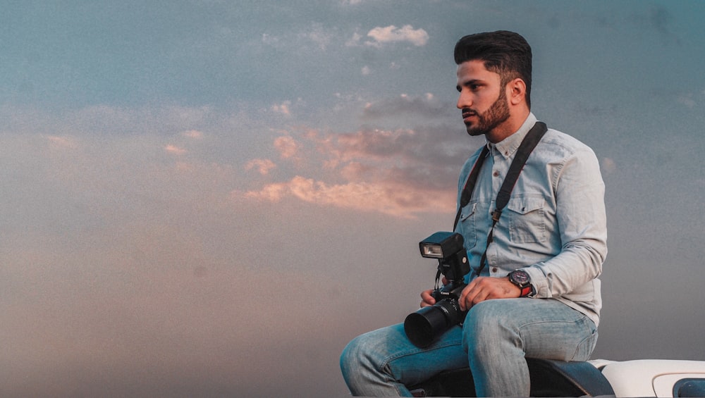 man sitting while holding DSLR camera