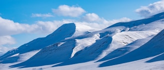 Snow-clad peaks and skiers gliding down the slopes of Gulmarg under a bright blue sky.
