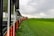 A retro train moving through a picturesque countryside with rolling hills and vibrant green fields.