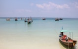 A traditional fishing boat bobbing in the turquoise harbor of a seaside town.