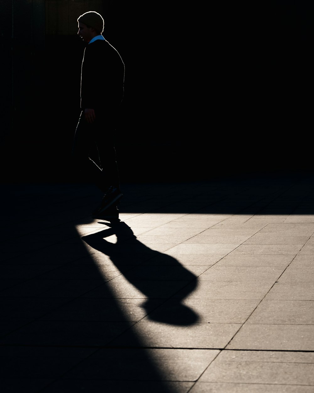 silhouette of man walking on pavement