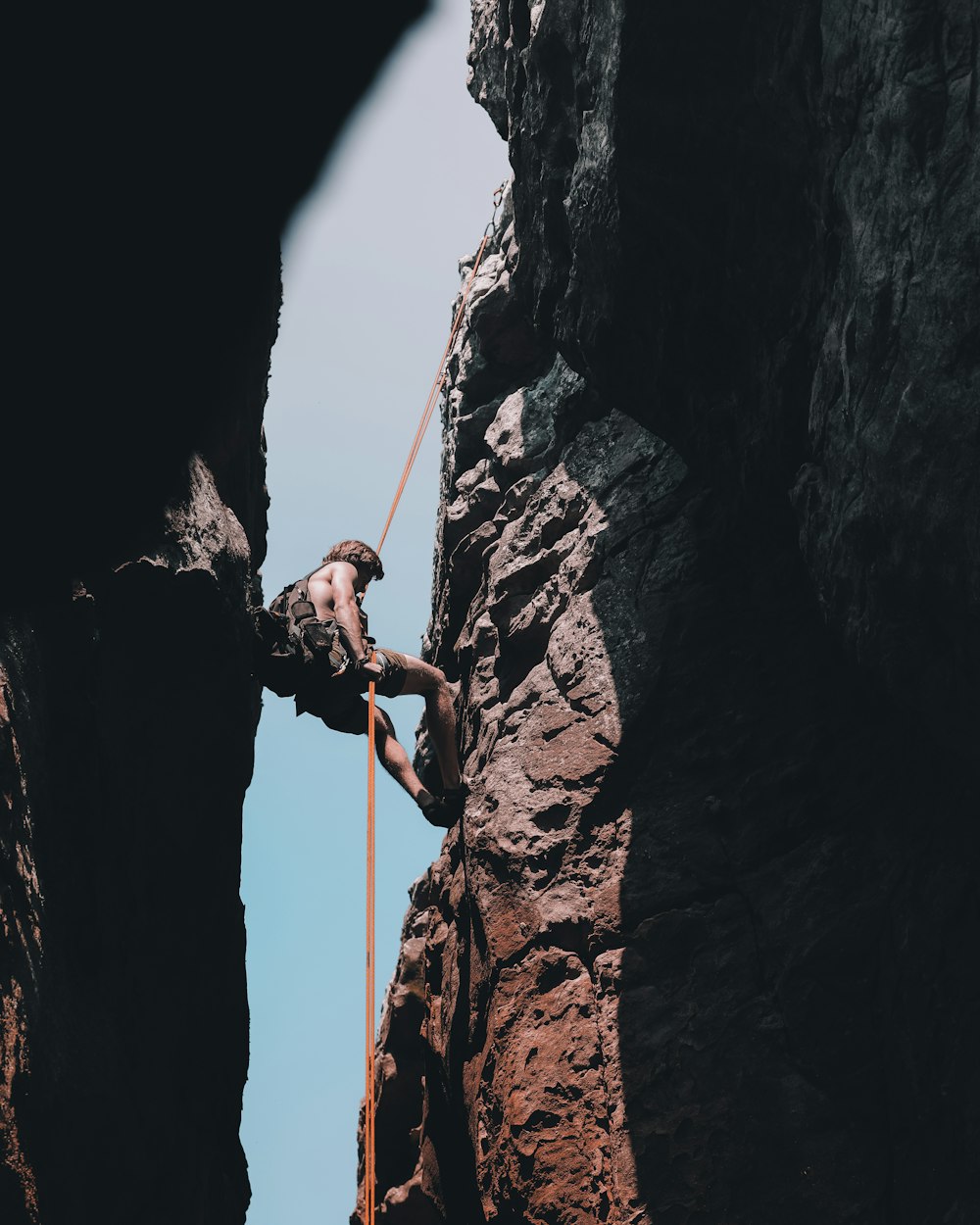 Un homme grimpant sur le flanc d’une montagne