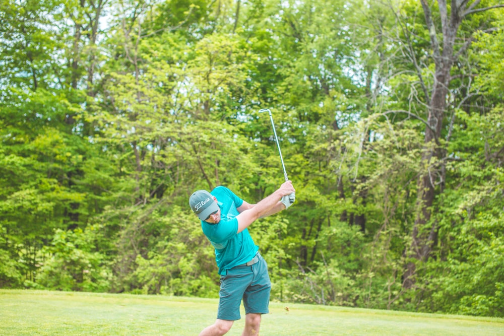 man playing golf near green trees during daytime