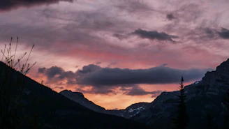 Aerial drone shot over a dramatic mountain landscape at sunset.