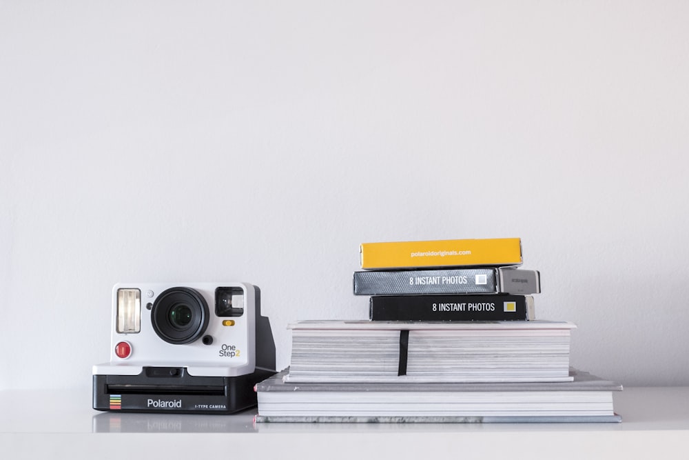 white and black Polaroid instant camera beside book