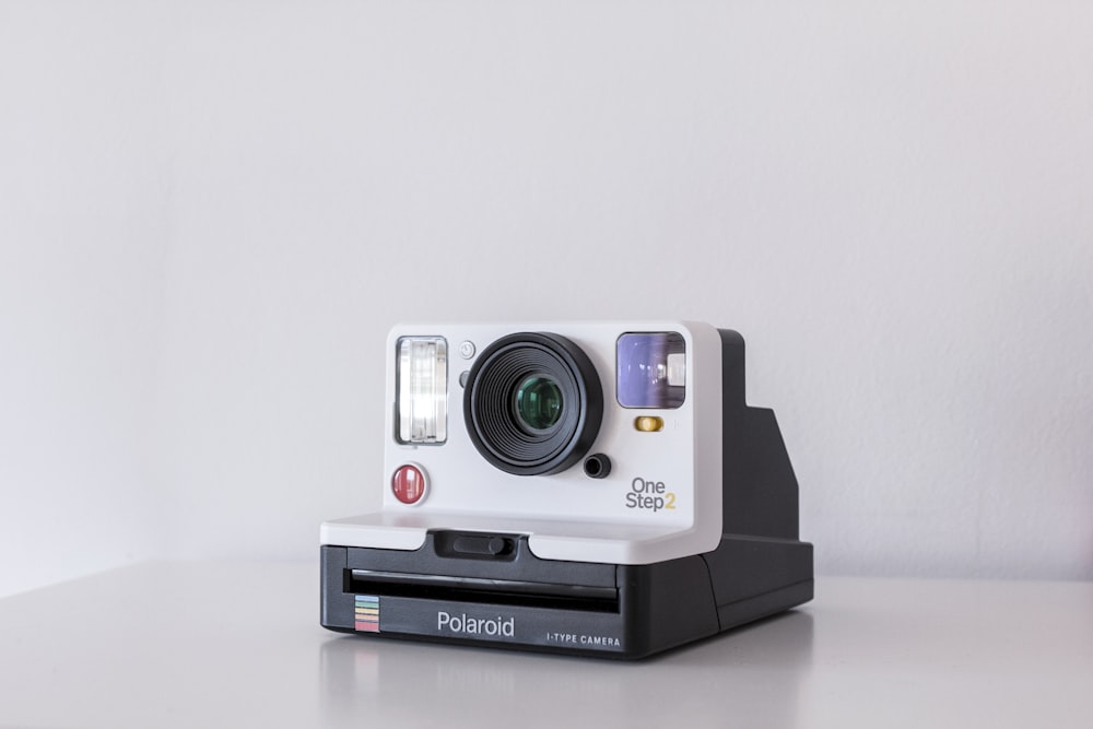 cámara instantánea Polaroid One Step 2 blanca y negra sobre pizarra blanca