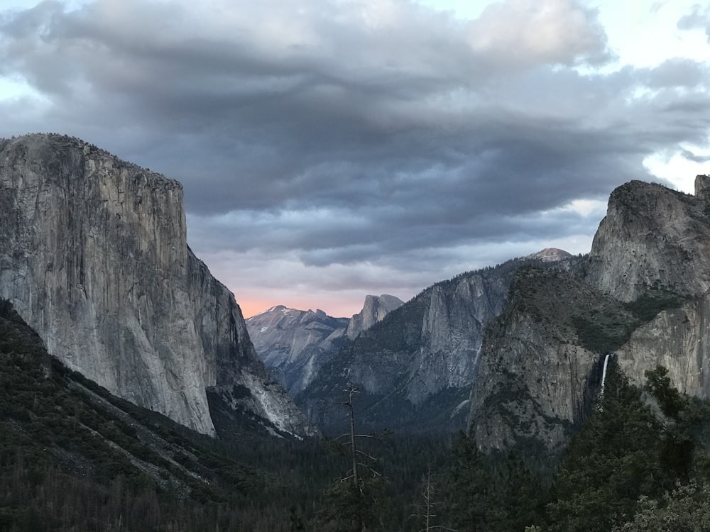 arbres verts près de la montagne sous ciel nuageux