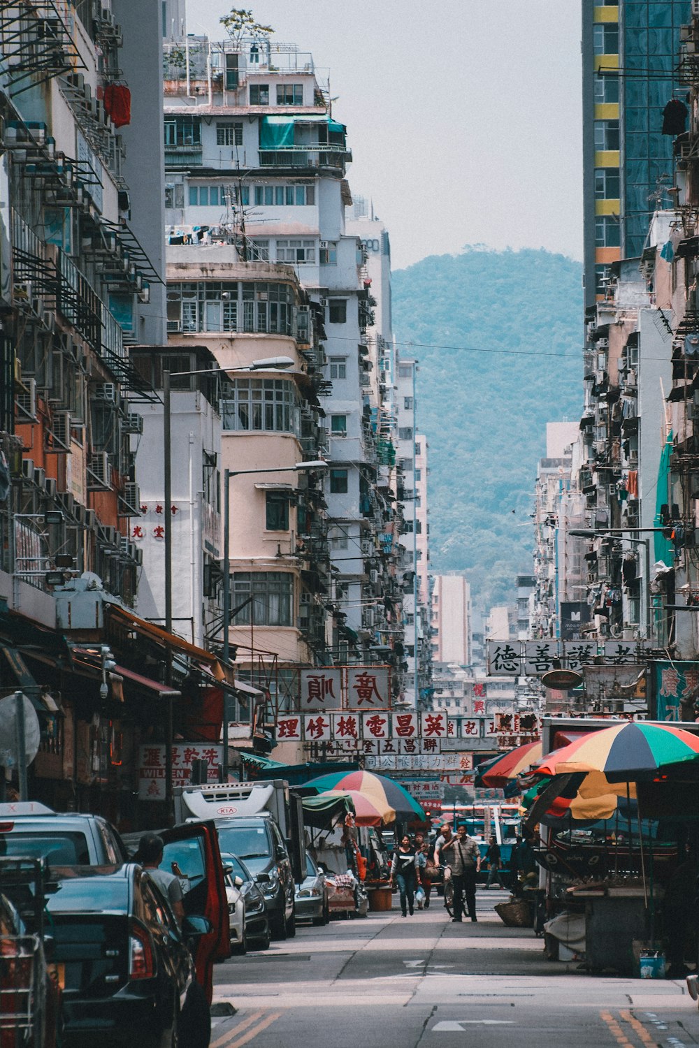 people walking between high rise buildings near mountain at daytime