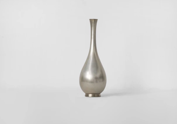 Close-up of a sleek, 3D printed geometric vase in matte black on a light grey surface.