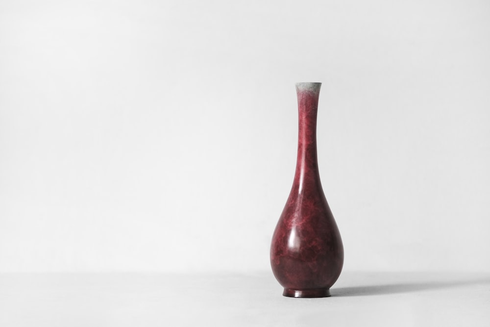 red ceramic vase on white surface