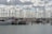 A harbor filled with numerous sailboats and yachts moored at docks. Tall masts reach up towards a sky filled with fluffy clouds. The water is calm, reflecting the array of vessels. One boat has 'Rescue' written on its side.
