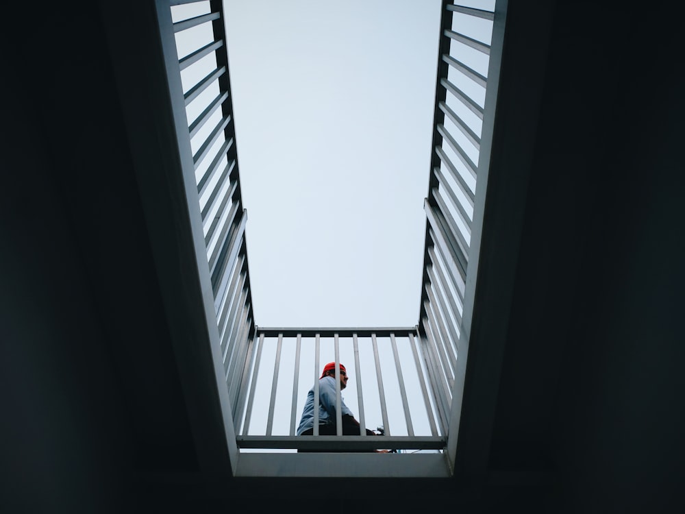 person sitting beside gray steel handrails