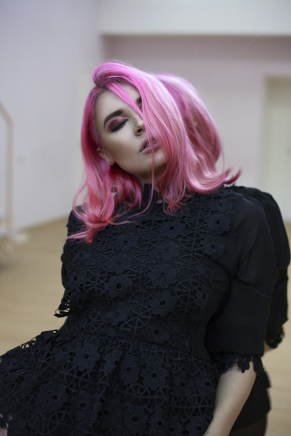 pink haired woman in black dress with eye closed