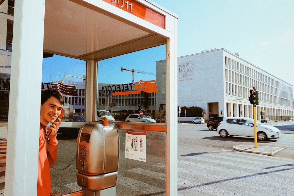 man holding phone of telephone booth