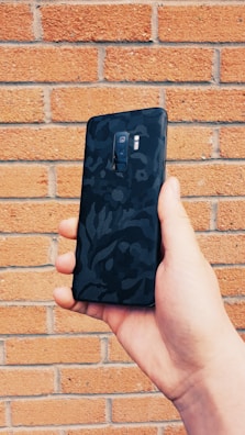 Stylish Vibetech phone case held by a hand against a textured concrete wall.